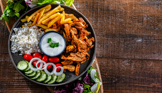Kebab served with rice, french fries, pitta bread, vegetables and tzatziki