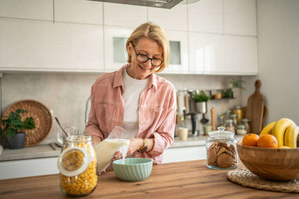 istock An elderly woman prepares a healthy breakfast, cornflakes with milk 1844602953
