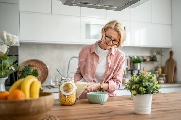 istock An elderly woman prepares a healthy breakfast, cornflakes with milk 1844602961