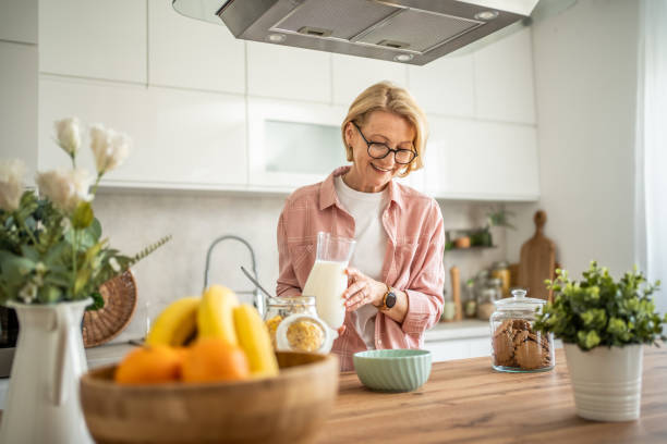 An elderly woman prepares a healthy breakfast, cornflakes with milk