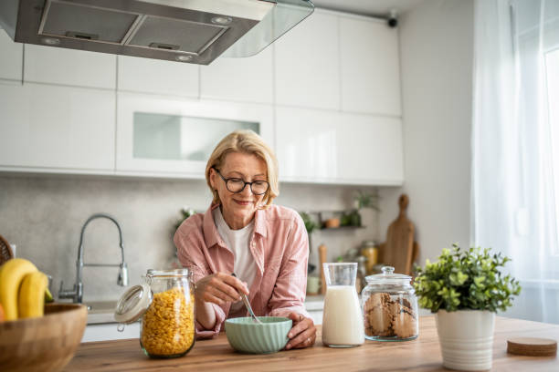 istock An elderly woman prepares a healthy breakfast, cornflakes with milk 1844603489