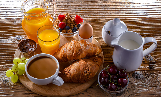 Breakfast served with coffee, orange juice, egg, cereals and croissants.