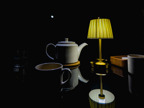 Restaurant, white teapot, white tea cup with tea, tea ceremony. Dark background
