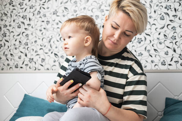 a mãe monitora o nível de glicose no sangue do filho pequeno usando um aplicativo de smartphone e um sensor remoto. - hypoglycemia diabetes child hyperglycemia - fotografias e filmes do acervo