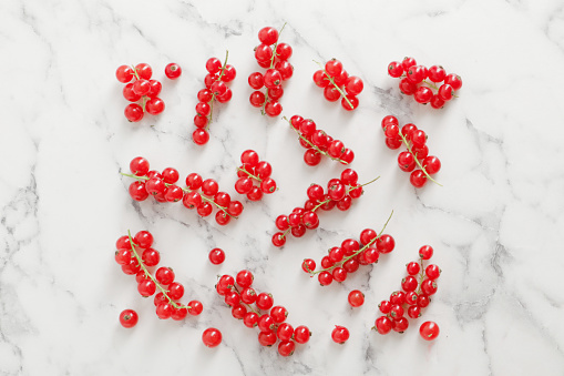 composition of ripe red currant berries on a textured marble background