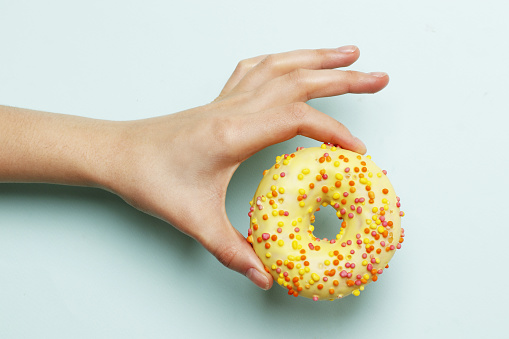 Woman holding delicious donut on color background