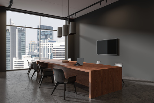 Dark negotiation interior with chairs and board, side view laptop and tv display on wall. Business conference corner with panoramic window on New York skyscrapers. 3D rendering