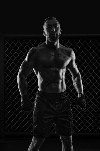 The dramatic black white image of the MMA fighter. Photography in a real octagon. Brutal fighter. Mixed media