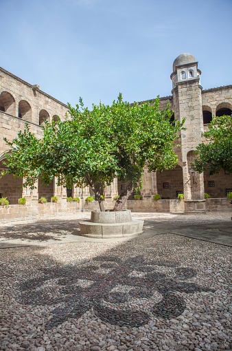 Alcantara, Spain - Oct 6th, 2022: Gothic Cloister of Convent of San Benito de Alcantara, Caceres, Spain. Alcantara cross on pebbles pavement