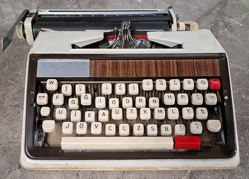 A vintage typewriter with sea foam green keys and a grey metal casing, shown isolated with shallow focus.