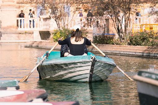 Seville, Spain; November 16th 2023: Woman rowing in a small boat in the canal of the Plaza de España in Seville. Tourists sailing in the canal of the Plaza de España.