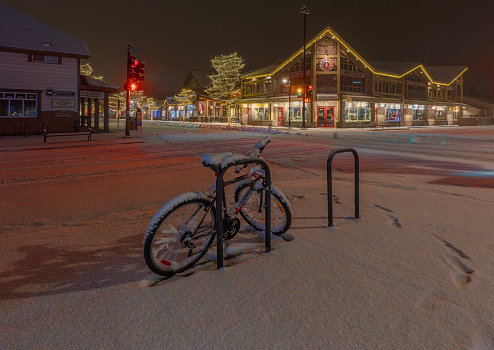 Bicycle in Christmas Snow at Canmore\nCanmore, Alberta, Canada – December 07, 2023:  Bicycle parked on Main Street on a snowy night