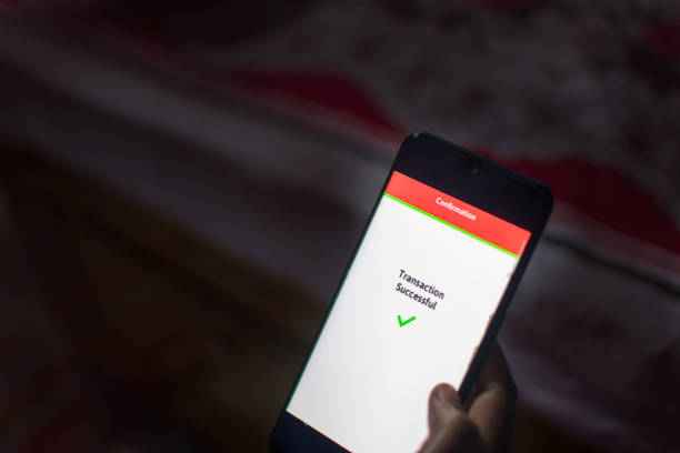 istock Woman Using Mobile Phone App To Authenthificate Bank Transfer . 1844812851