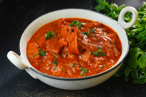 cup of tasty soup, hot and steaming with beef, vegetables, curry, turmeric and clove seeds