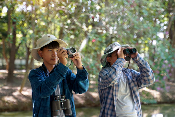 istock Two Asian boys use binoculars and a camera to study the local birds in a community forest. 1844863908