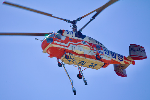 Ulsan, South Korea - June 21, 2023: A close-up view of a firefighting helicopter, focusing on the dangling hoses set against a backdrop of the vast blue sky, highlighting its readiness for action.