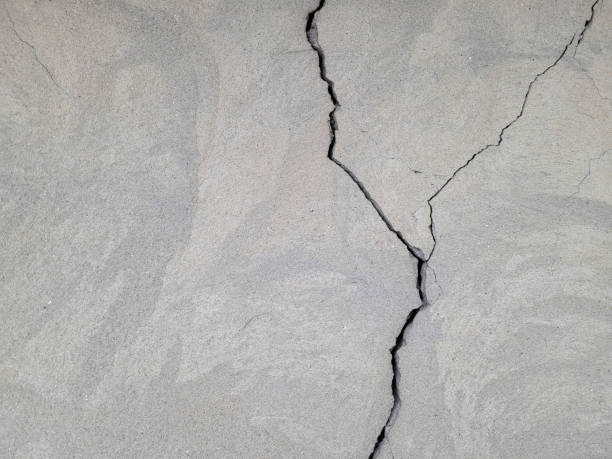 istock Cracked concrete surface covered with gray cement mortar. Destruction after the earthquake. Rough winding cracks on the wall. copy space. Texture background 1844893309