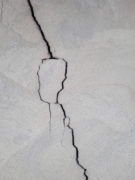 istock Vertical uneven crack on the wall. Cracked concrete wall covered with gray cement mortar. Destruction caused by an earthquake. copy space. Texture background 1844894258