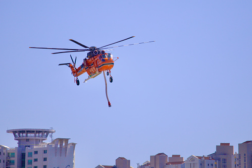 Ulsan, South Korea - June 21, 2023: A firefighting helicopter descends for landing, framed by towering apartment buildings in the background, merging urban landscapes with emergency aviation.