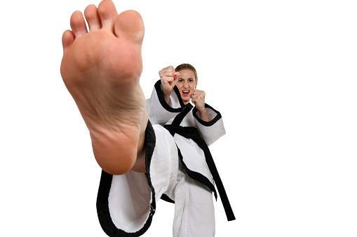 Martial artist executing a front kick with yell.