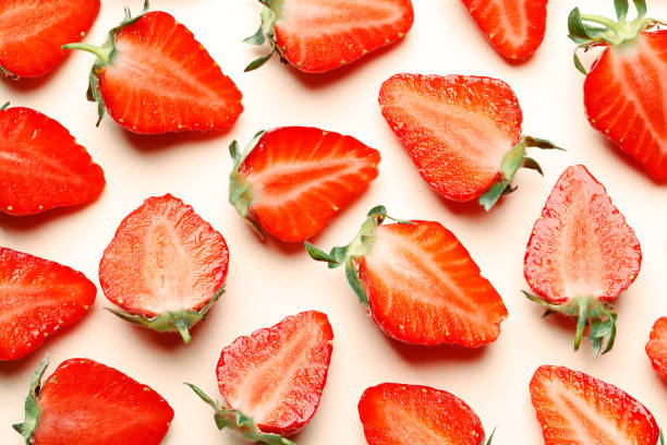 Ripe juicy strawberries on a pink background. pattern. Creative summer background composition with strawberry slices. Minimal fruit concept.