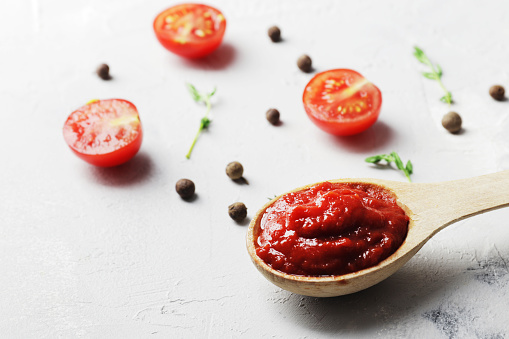 composition of tomato sauce and allspice, Thyme spread on marble. Tomato sauce in a wooden spoon and spices on a marble background.