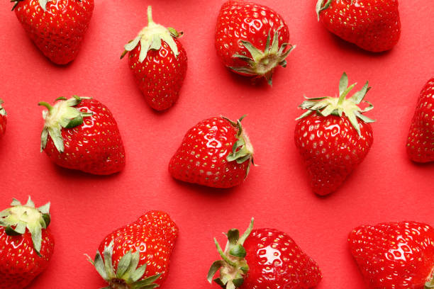 istock Ripe juicy strawberries on a red background. pattern. Creative summer background composition with strawberry. Minimal fruit concept. 1844970400