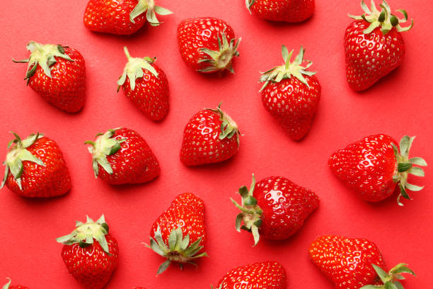istock Ripe juicy strawberries on a red background. pattern. Creative summer background composition with strawberry. Minimal fruit concept. 1844970418
