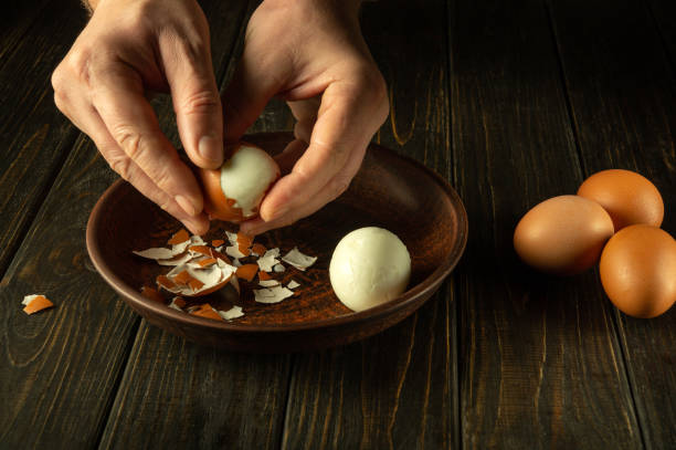 istock Preparing a delicious breakfast with boiled eggs on the kitchen table. Peeling an egg from the shell by a man hands. Egg diet concept 1844974676