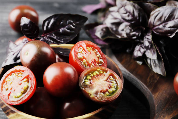 istock Fresh ripe black cherry tomatoes with basil on textured background 1844984599