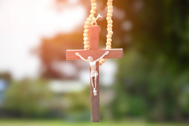 Wooden cross hanging on tree branch, soft and selective focus, natural bokeh tree background, concept for hope, love, forgiveness and belief in Jesus around the world.