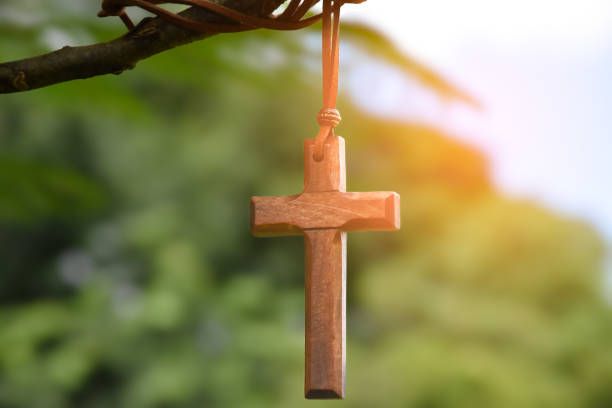 Wooden cross hanging on tree branch, soft and selective focus, natural bokeh tree background, concept for hope, love, forgiveness and belief in Jesus around the world.