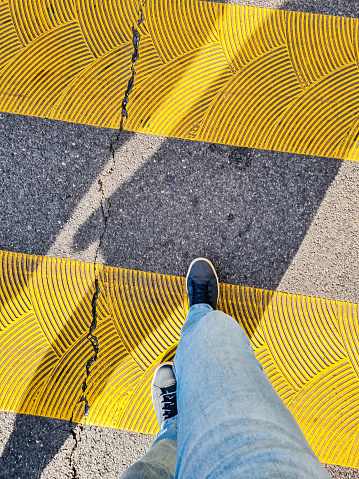Personal perspective of pedestrian crossing the street on yellow zebra crosswalk in Geneva, Switzerland.