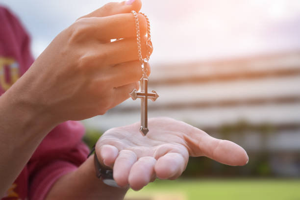 Wooden cross holding in hand, soft and selective focus, natural bokeh tree background, concept for hope, love, forgiveness and belief in Jesus around the world.