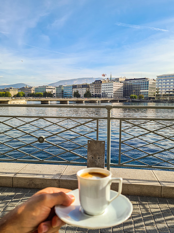 Personal perspective of a man drinking coffee at Geneva Lake in Switzerland.