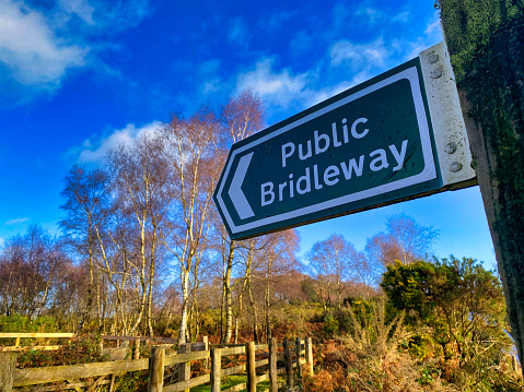 A photograph of a public footpath sign at Woodbury Common in Devon, UK.
