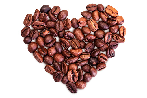 Cup of coffee with roasted raw coffee beans making a heart shape