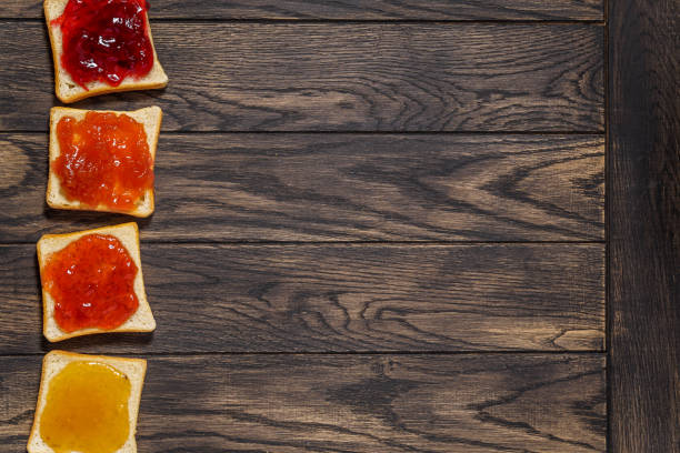 Four toasted bread with different jams on left side of table above