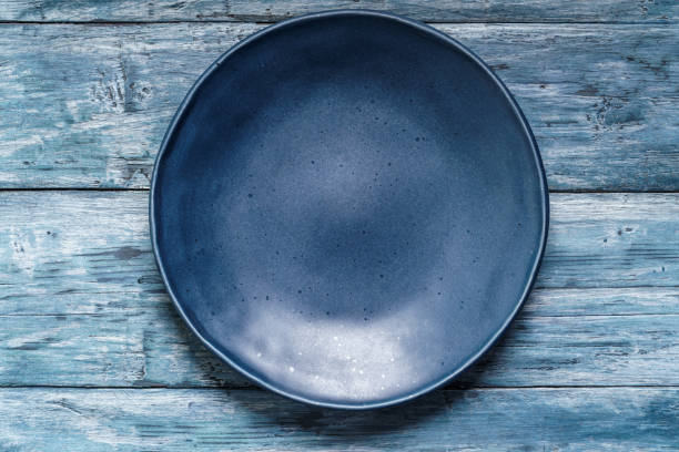 istock Empty blue plate on old shabby wooden table 1845038215
