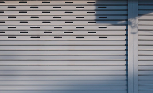 Gray steel Roller Shutter Door Background with sunlight and shadow on surface