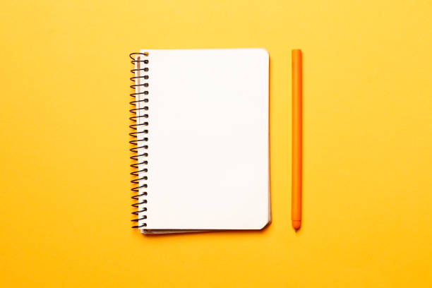 istock blank paper notebook with pen on yellow background 1845050983