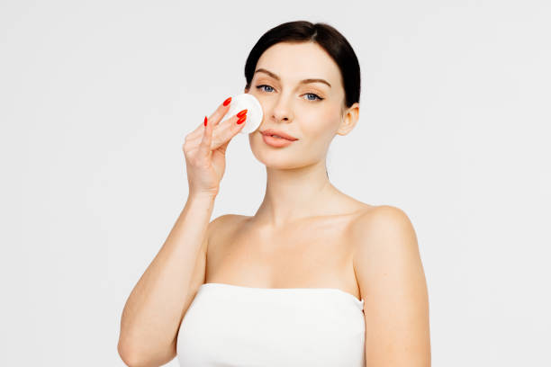 istock Charismatic, beautiful young woman using a cotton pad on a light isolated background. Concept of clean skin, facial care and natural cosmetics. 1845070896