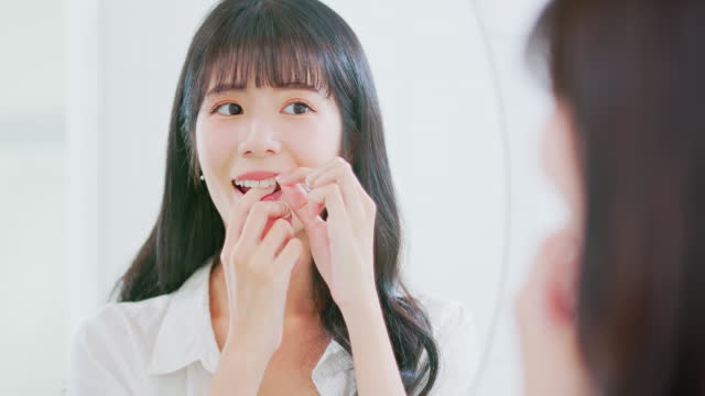 asian woman happily flossing teeth