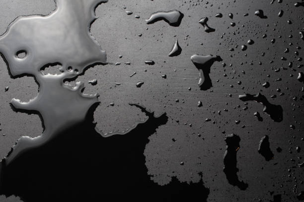 Water drips falling on a water resistant tile flooring. Black and blue tones with copyspace on the left side. Concept of water leakage and insurance