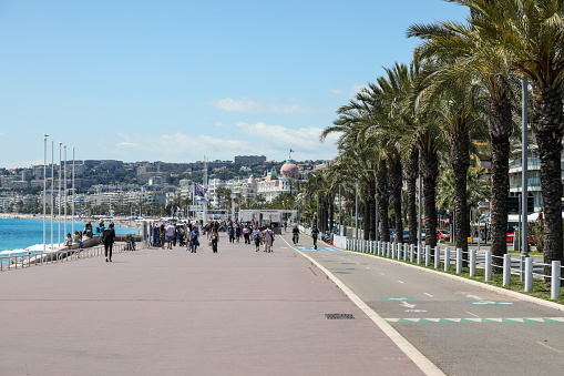 Nice, France - May 3, 2023: The Promenade des Anglais is the perfect place to relax. In the distance, people stroll along this wide seafront promenade.