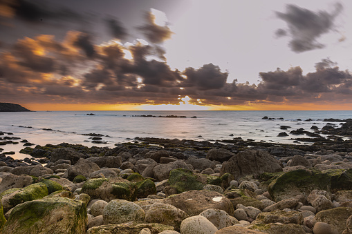 Vibrant sunset over the horizon of the ocean with a rocky shoreline in Sao Martinho do Porto, Portugal