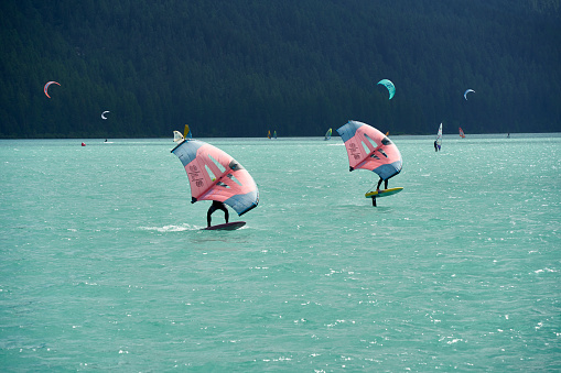Engadin, Switzerland - July 16, 2023: Wing foiling on the lake. Water sports enthusiasts surfing with equipment from duotone.