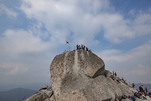 seoul, south korea - october 23, 2023: people hiking and climbing to baegundae mountain and resting at the peak in bukhansan national park in seoul.
