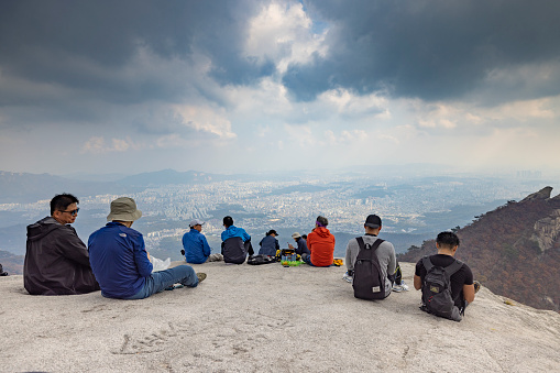 seoul, south korea - october 23, 2023: people hiking and climbing to baegundae mountain and resting at the peak in bukhansan national park in seoul.