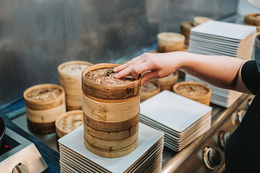 dim sum dumplings steamed in a kitchen restaurant are being stacked and ready to be served